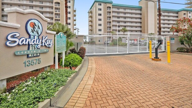 A gated entrance to a building complex with a sign reading 'Sandy Key Condominiums 13575'. - Sandy Key 635: 2 BD/2BH, 6th floor (Pensacola)