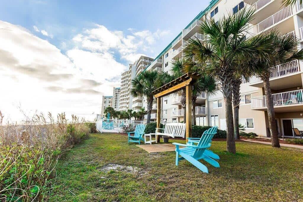 Un hôtel doté de nombreux balcons, d’un espace extérieur aménagé et de palmiers.
