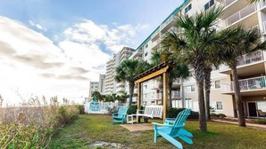 A hotel with multiple balconies, outdoor seating, and palm trees. - Sandy Key 635: 2 BD/2BH, 6th floor (Pensacola)