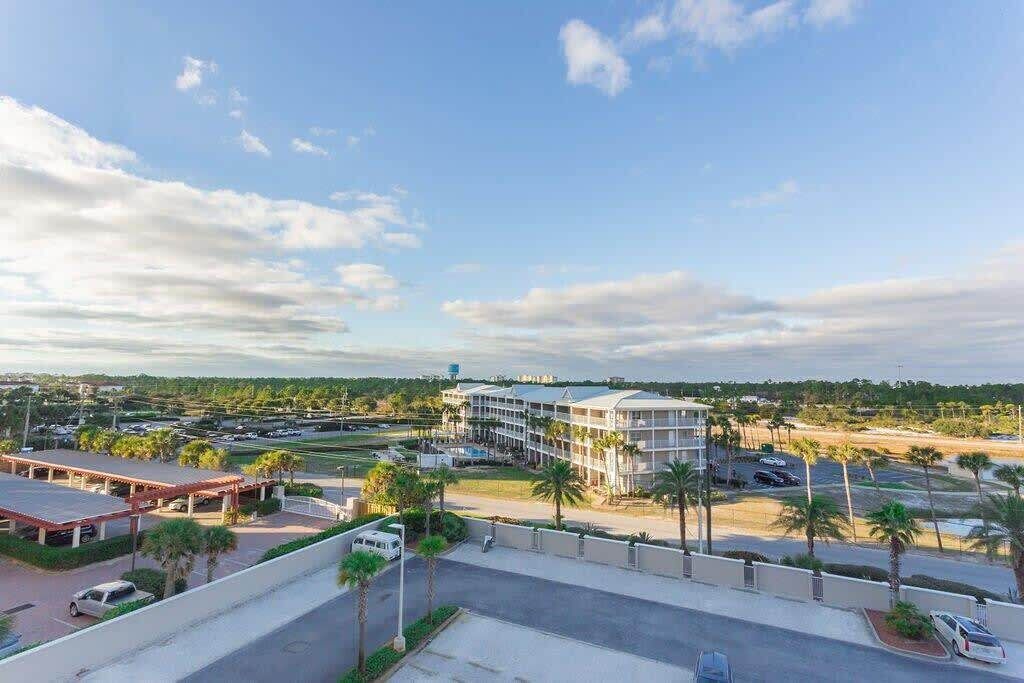 A hotel with a parking lot, a swimming pool, and a view of the surrounding landscape.