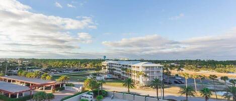 A hotel with a parking lot, a swimming pool, and a view of the surrounding landscape.