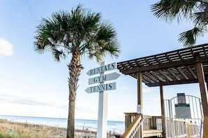 A beachside signpost with directions to rentals, gym, and tennis facilities.