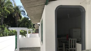 Ein kleiner, abgeschlossener Patio-Bereich mit einer weißen Wand, einem Betondach und einer weißen Tür, die nach innen führt.