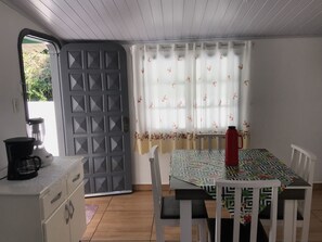 A dining area with a table, chairs, a coffee maker, and a door.