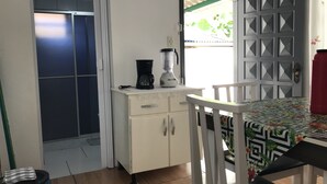 Eine kompakte Küche mit Kaffeemaschine, Mixer und einem kleinen Tisch mit Blumenmuster-Tischdecke.