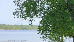 En strand vid en sjö med en brygga, solstolar och ett picknickbord.
