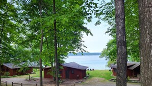 Ett område vid sjön med flera stugor byggda av trä, en grusgång och utsikt över sjön.