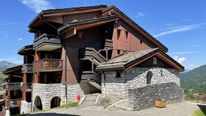 A multi-story wooden chalet with stone foundations, balconies, and a stone entrance. - Le Portail 19 - Beautiful 2-room apartment, overlooking the slopes and the valley (LES AVANCHERS VALMOREL)