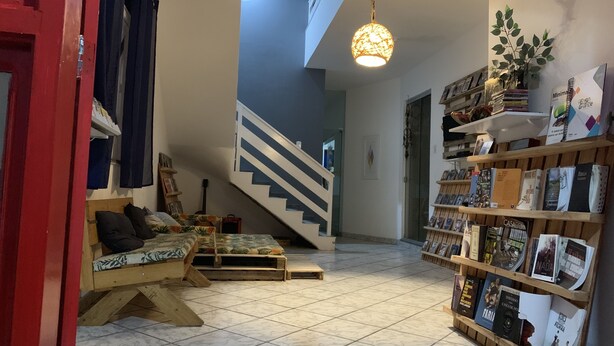 Un salon chaleureux avec un banc en bois, un escalier et une bibliothèque remplie de livres.