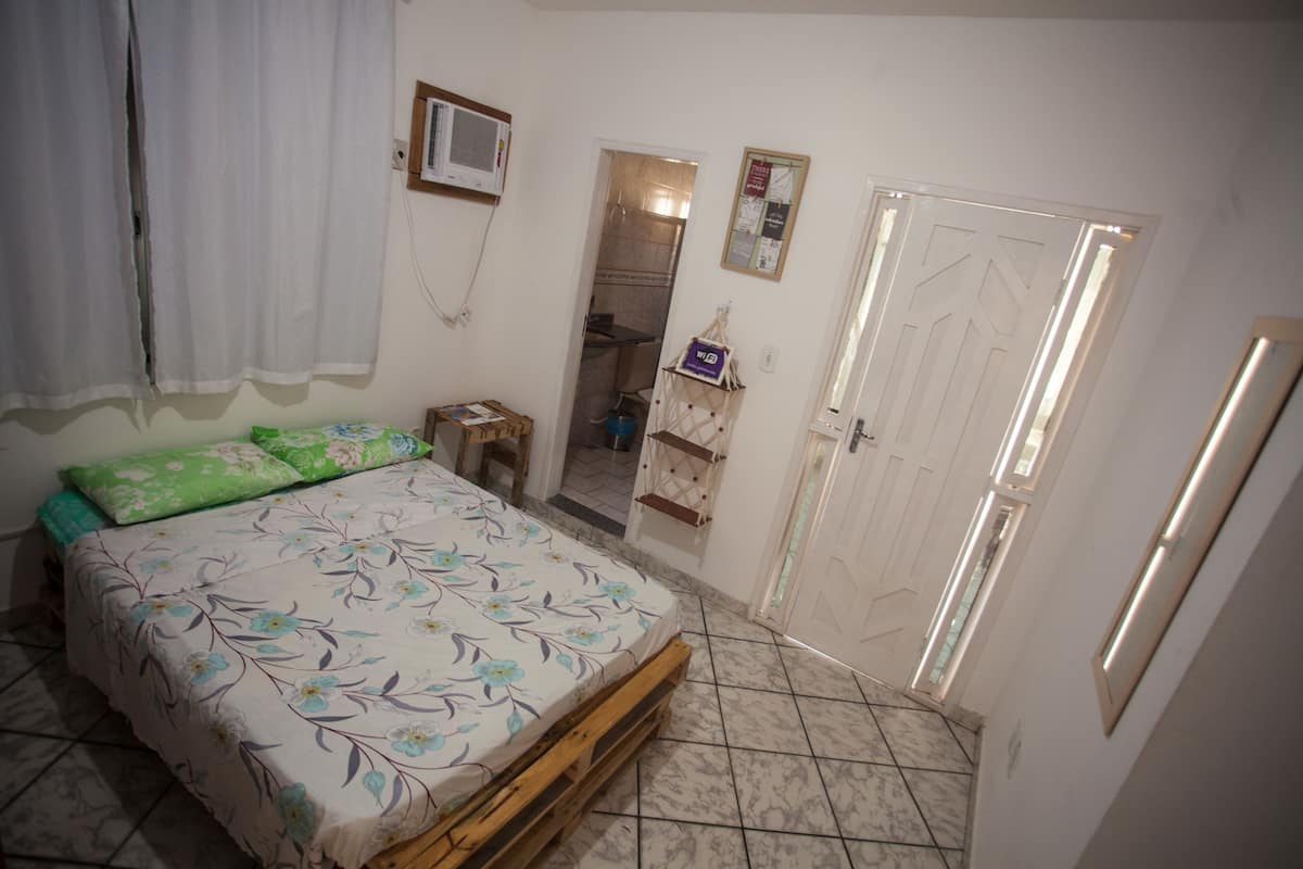 A bedroom with a bed, a wooden bench, a small table, and a wardrobe.