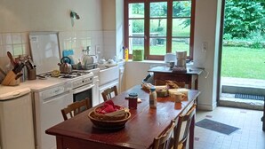 Une cuisine avec un plafond en bois, une table à manger avec des chaises et une vue sur un jardin par une fenêtre.