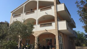 A multi-story building with balconies, arched windows, and a flat roof.