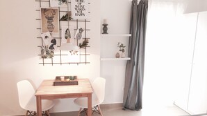 A modern room with a wooden dining table, two white chairs, a world map on the wall, and a grey curtain.