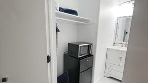 Un bagno piccolo con un lavandino bianco, uno specchio e un frigorifero nero.