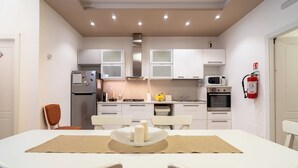 A compact kitchen with white cabinets, a microwave, a stove, and a fire extinguisher.