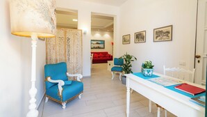 A room with a white table, a blue chair, a red sofa, and a decorative screen.