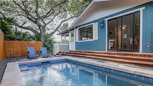 A swimming pool with a wooden deck, a covered patio, and a view of a house with large windows and a sliding door. - Sleeping Giant Cottage with Plunge Pool TNVC #1244 (Kapaa)