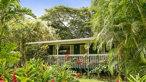 A house with a porch surrounded by lush tropical vegetation. - Sleeping Giant Cottage with Plunge Pool TNVC #1244 (Kapaa)