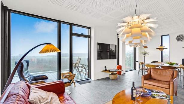 Un salon moderne doté d’une grande fenêtre, d’un canapé, d’une table basse et d’un coin repas.