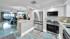 A modern kitchen with stainless steel appliances, a marble backsplash, and a view to the outside.