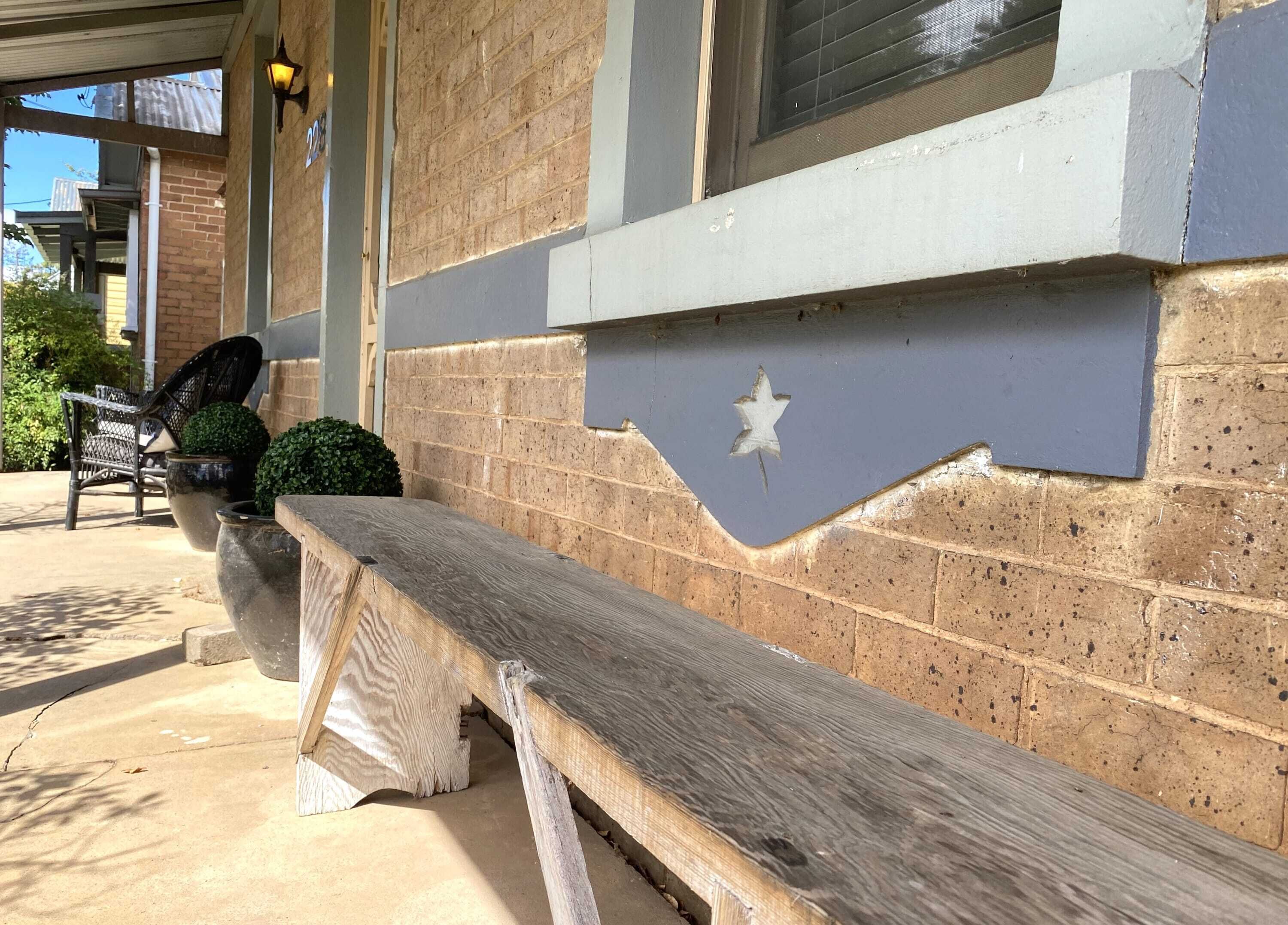 A building exterior with a wooden bench, a star-shaped cutout, and a brick wall.