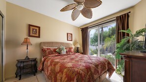 A bedroom with a large bed, a ceiling fan, a nightstand with a lamp, and a view of the outdoors through a window. - 122LQ LOOKING NORTH/WEST ON THE NICKLAUS PRIVATE WHAT AN AWSOME MOUNTAIN VIEW AND QUIET (La Quinta)