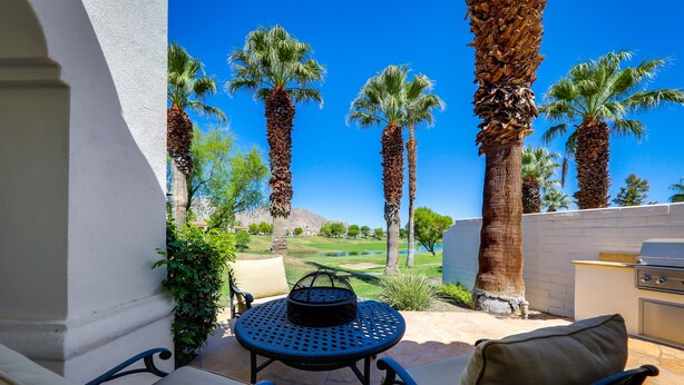 A patio with a round table and chairs, a grill, and tall palm trees. - 122LQ LOOKING NORTH/WEST ON THE NICKLAUS PRIVATE WHAT AN AWSOME MOUNTAIN VIEW AND QUIET (La Quinta)
