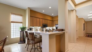 A spacious kitchen with a central island, wooden cabinets, and a large window with blinds. - 122LQ LOOKING NORTH/WEST ON THE NICKLAUS PRIVATE WHAT AN AWSOME MOUNTAIN VIEW AND QUIET (La Quinta)