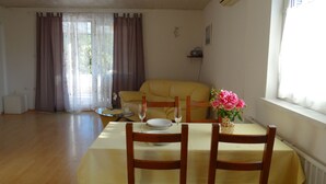 A dining area with a table set for two, a sofa, and a window with curtains.