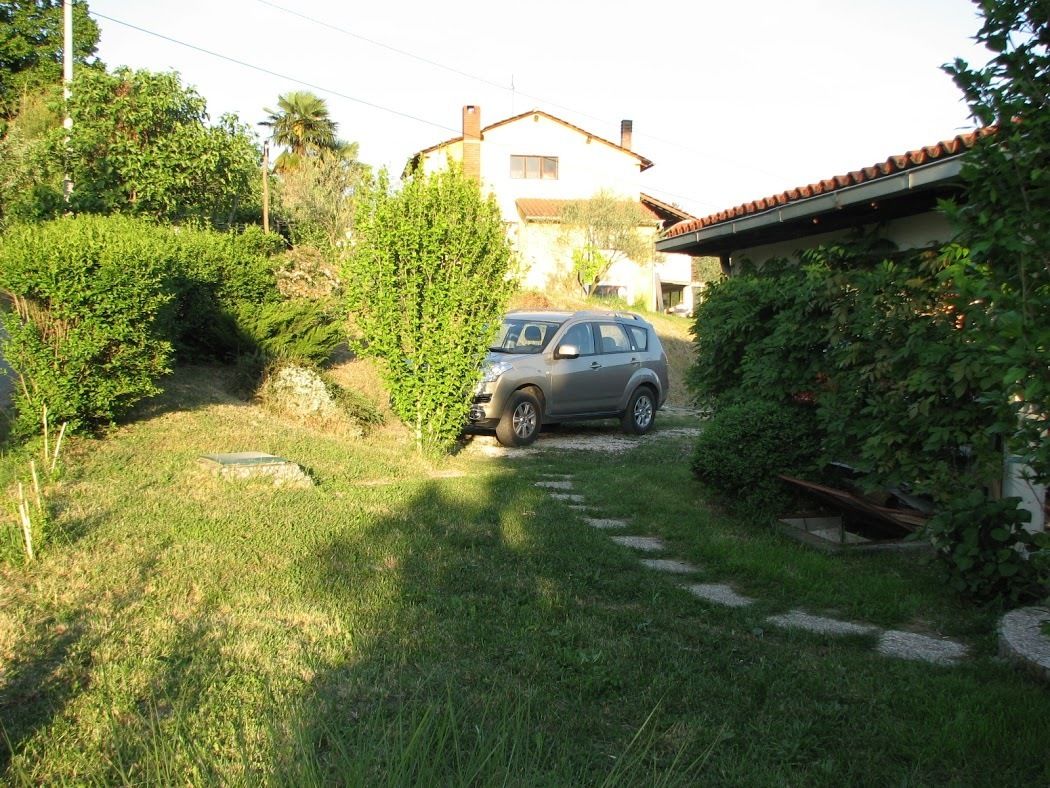 Un'auto parcheggiata in un vialetto, con una casa sullo sfondo.