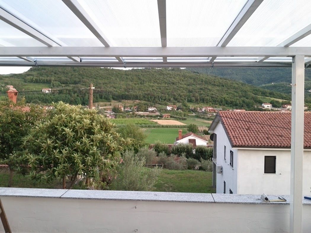 Une vue depuis un balcon abrité, donnant sur un paysage rural avec des maisons et de la végétation.