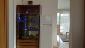A kitchen with a white refrigerator, wooden cabinets, and glass shelves with blue lights.
