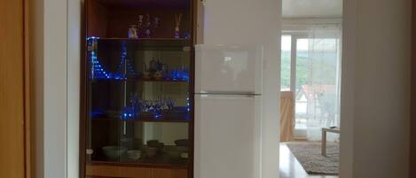A kitchen with a white refrigerator, wooden cabinets, and glass shelves with blue lights.