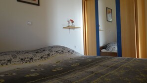 A bedroom with a bed, a bedside table with a vase, and a door leading to another room. - Bonini Apartments - Adults Only (Koper)