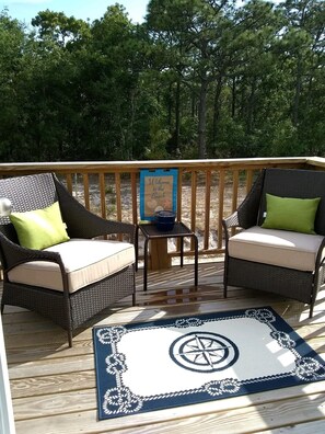 A wooden deck with wicker furniture and a welcome sign. - JDs Place (Carolina Beach)