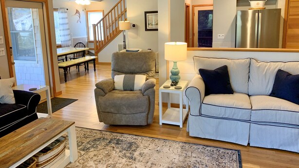 A living room with a sofa, armchair, and a dining area with a table and chairs.