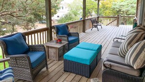 A covered outdoor deck with wicker furniture, a table, and a bench.