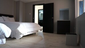Ein Schlafzimmer mit einem Bett, einer Tür zu einem Badezimmer und einem kleinen Schrank.