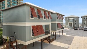 A two-story building with a flat roof and multiple windows with red shutters. - Stunning updated cottage on the beach! (Orange Beach)