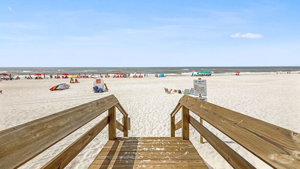 A wooden boardwalk leading to a sandy beach with umbrellas and beach chairs. - Stunning updated cottage on the beach! (Orange Beach)