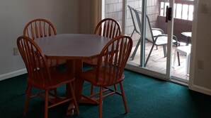 Un coin repas avec une table et des chaises, un luminaire suspendu, une horloge et une vue sur l’extérieur grâce à une porte-fenêtre coulissante.