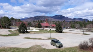 Un parking avec une voiture verte, un kiosque et un bâtiment doté d’une tour horloge.