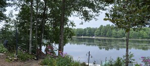A serene lakeside view with a dock, surrounded by lush greenery and flowering plants. - Lakeside Gardens, New Waterfront Property, 1100 sq. ft,  2 Bed, 1 Bath Sleeps 6 (Mountain)