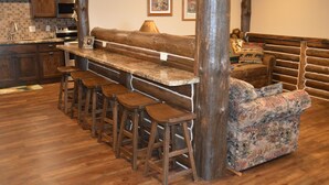A rustic kitchen with wooden bar stools, a wooden bench, and a patterned sofa.