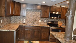 A kitchen with wooden cabinets, a granite countertop, a stainless steel microwave, and a built-in oven.