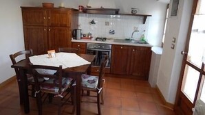 Una cocina compacta con armarios de madera, una mesa de comedor con sillas y piso de baldosas.