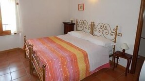 Un dormitorio con cama, mesita de noche, lámpara y aplique de pared.