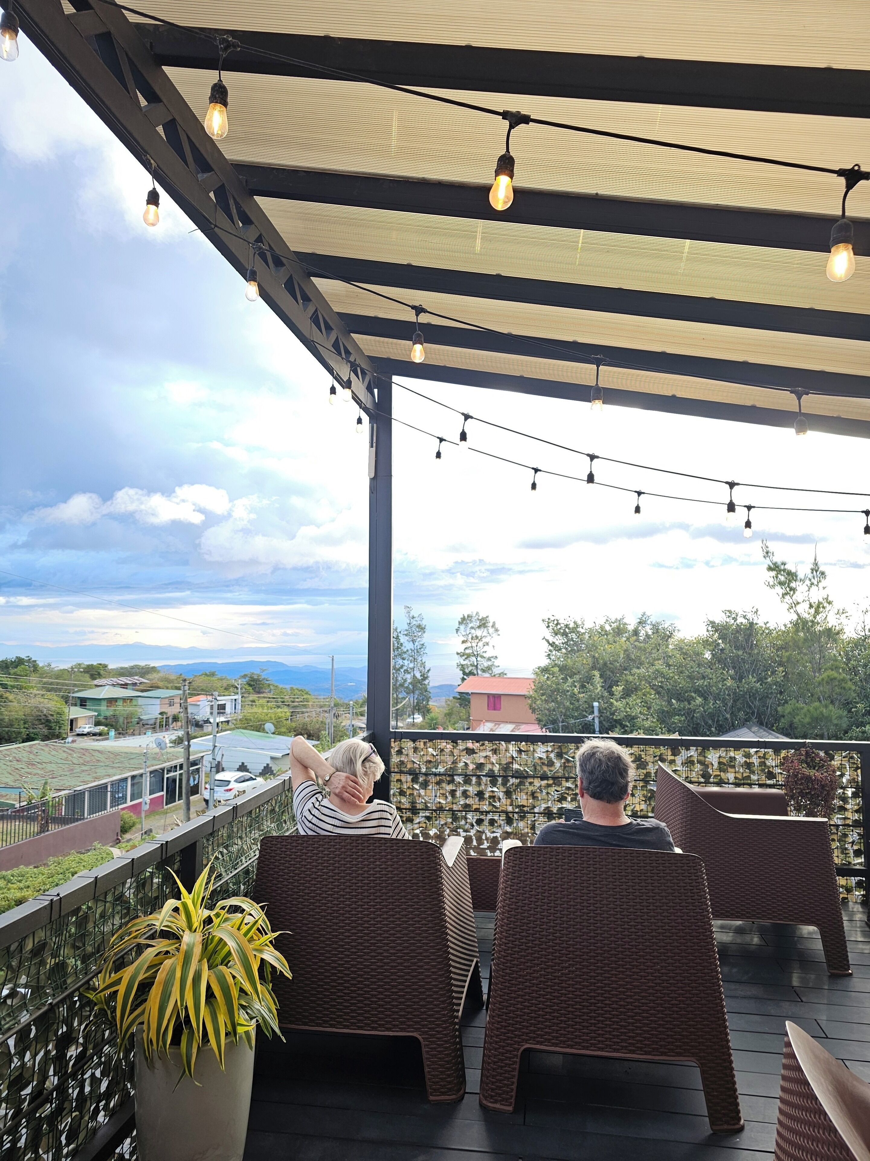 A covered outdoor seating area with wicker furniture and string lights.