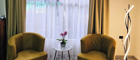 A room with two armchairs, a small round table with a potted plant, and a floor lamp.
