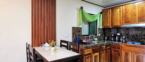 A modern kitchen with wooden cabinets, a marble countertop, and a dining area with a table and chairs.